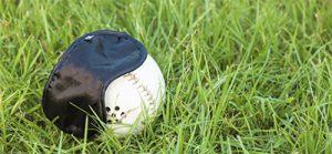 A beep baseball and blindfold rest together on a grassy backdrop.